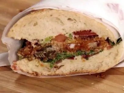 Oyster po boy is served on a French roll with oysters, plum tomatoes, jalapenos, and arugula.