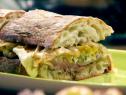Ciabatta cheese steaks are made with grilled flat iron steaks, lettuce, provolone cheese, onions, and a nutmeg sauce.