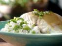 Sake steamed bass is served on a bed of ginger edamame rice and topped with a soy beurre blanc and chives.