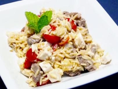 Braised lamb orzo salad with roma tomatoes and a garnish of mint.
