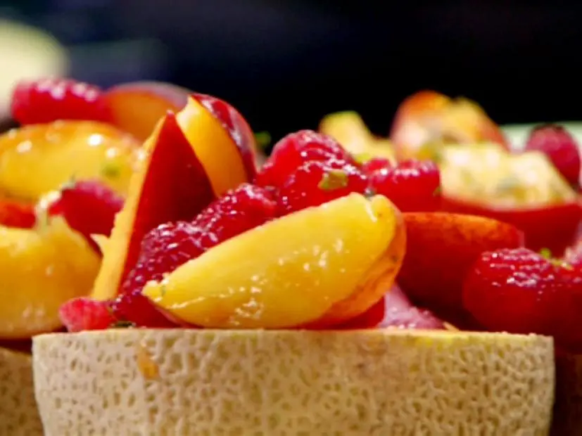 Melon melba bowls are halved cantaloupes with the seeds scooped out and filled with raspberry sorbet then topped with a peach and raspberry Melba topping.