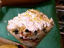 A large parfait topped with whipped cream and sprinkles of orange zest and oats