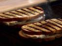Two grilled mozzarella cheese sandwiches cooking on a grill