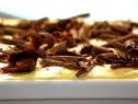 Tiramisu covered with shaved chocolate in a white dish