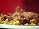 A steak and bacon mixture on a bed of pasta against a red background
