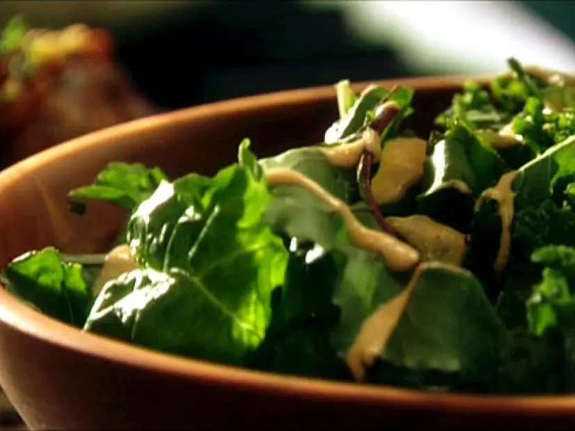 A salad drizzled with Pear Walnut Dressing in a wooden bowl