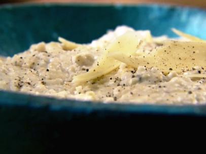 Grits topped with Gruyere Cheese and cracked pepper in a textured turquoise bowl
