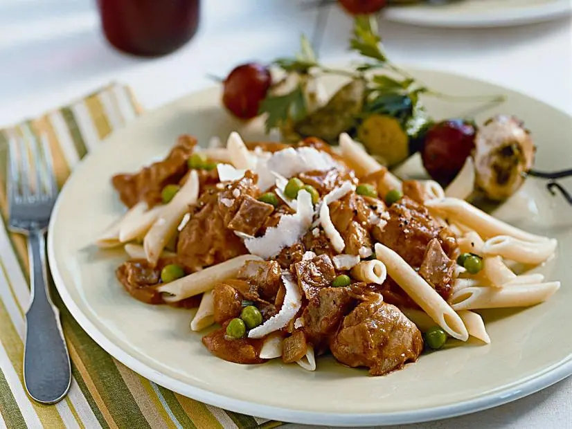 Chicken and Peas atop pasta on a plain light green plate