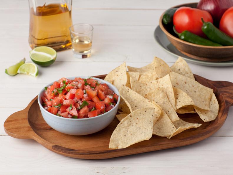 Tortillas and salsa in a small gray dish on top of an oval wooden tray