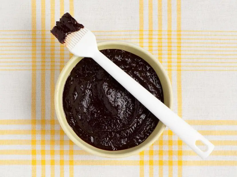 A chili coffee sauce in a light yellow bowl on top of a white and yellow plaid tablecloth