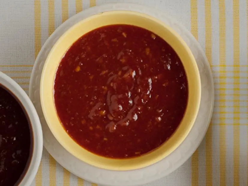 A sweet and sour sauce in a yellow bowl placed on a small white dish