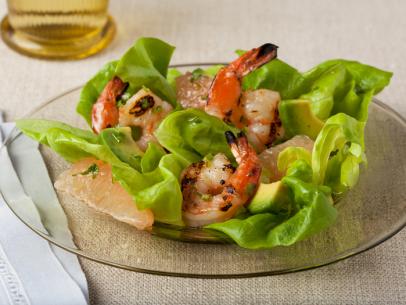 Shrimp with sauce on a piece of lettuce lying on a clear glass plate