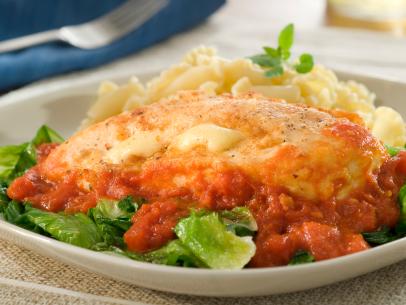 Stuffed Chicken Breast in a pool of tomato sauce placed on a bed of fresh greens