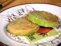 Two fried green tomatoes on a white plate with black cursive writing
