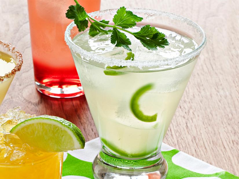 A maragarita  in a short glass containing slices of lime and a mint spring