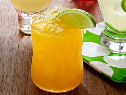 An orange colored margarita in a short glass garnished with a lime wedge