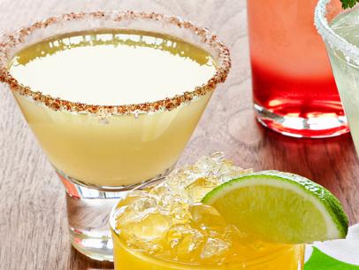 Various colored and sized margaritas placed on a wooden surface