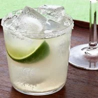 A maragarita in a short glass placed on a round wooden tray
