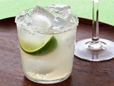 A maragarita in a short glass placed on a round wooden tray