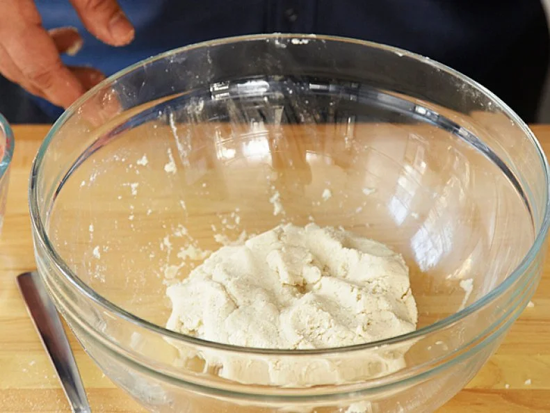A lump of dough placed in a plain clear glass bowl