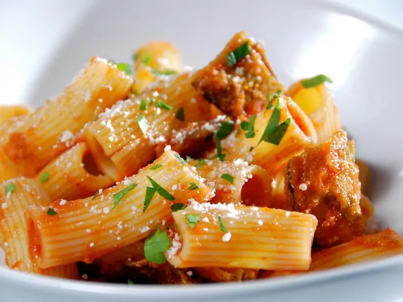 Eggplant pasta sprinkled with herbs in a plain white dish