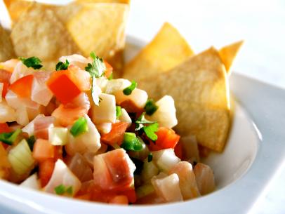 Raw fish and vegetable mixture along with tortilla chips in a plain white dish