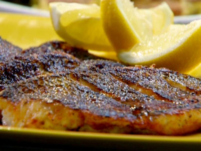 Smoky spicy bass is served with lemon wedges.