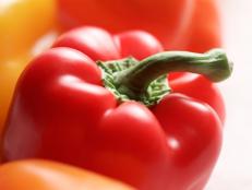 A close-up of a red pepper amongst other red and yellow peppers