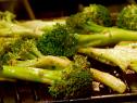 Several seasoned broccoli spears on a grill