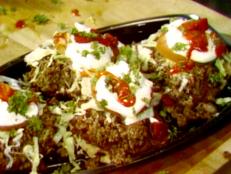 This could be referred to as a Mexican hamburger made with chopped beef, chili beans, fried tortillas and refried beans, topped off with chopped onions, lettuce and sour cream.