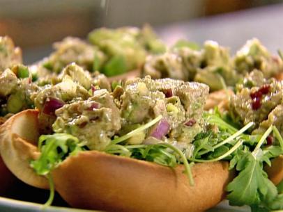 Tuna salad on a bed of arugula placed within hot dog rolls 