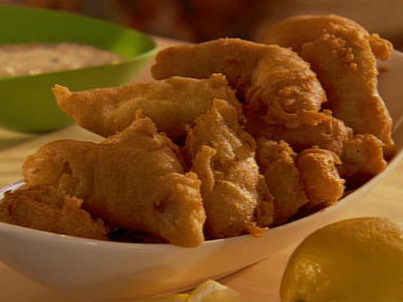 Several pieces of fried catfish filets placed in a plain white boat shaped dish