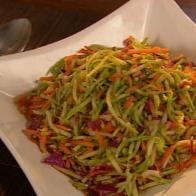 Cole slaw in a white diamond shaped dish thats placed on a wooden surface