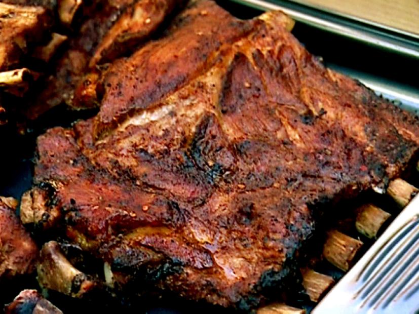 A close-up of a baking pan full of partial slabs of ribs