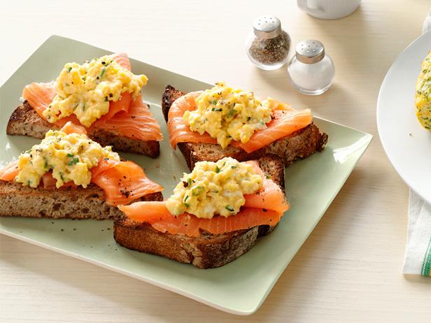 Pieces of toast topped with salmon and another herbed topping that are placed on a small pale green plate
