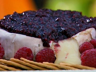 Brie topped with a raspberry mixture and surrounded with whole raspberries and crackers