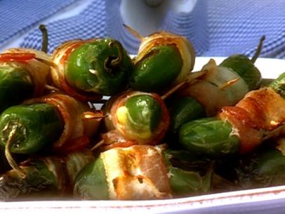 Grilled jalapeno peppers wrapped in bacon on a simple white plate