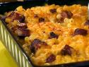 Baked macaroni and cheese with pieces of chopped hot dogs in a green, white and black baking pan