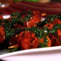 Morroccan Chicken drizzled with a green herb sauce on a simple square white plate