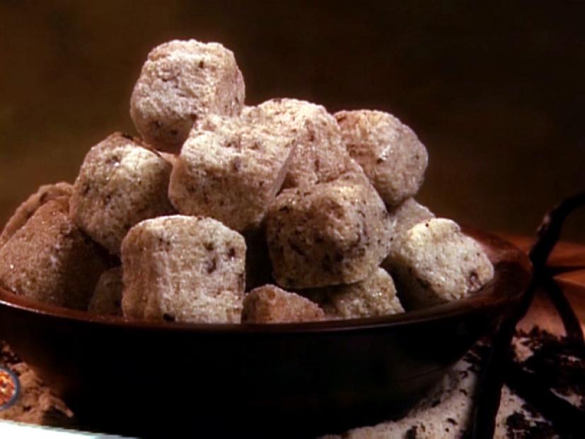 Vanillla Bean Sugar Cubes piled up in a stall brown bowl surrounded bay sugar and vanilla beans