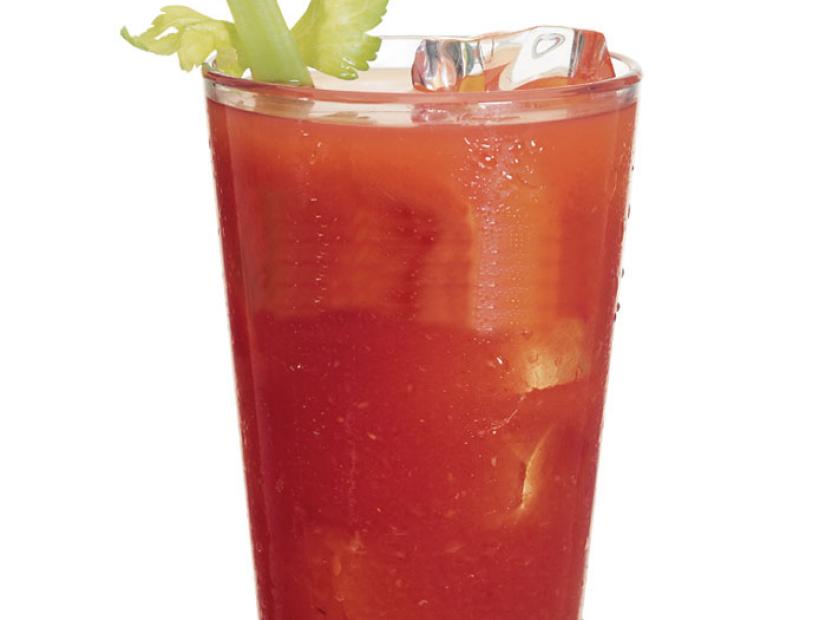A Bloody Mary on ice garnished with a celery stalk in a beer glass