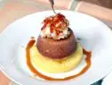 Banana coconut luau cake is placed on a pineapple ring and topped with macadamia brittle and coconut caramel sauce.