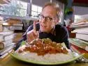 Lamb tikka masala served on a bed of white rice and topped with fresh herbs.