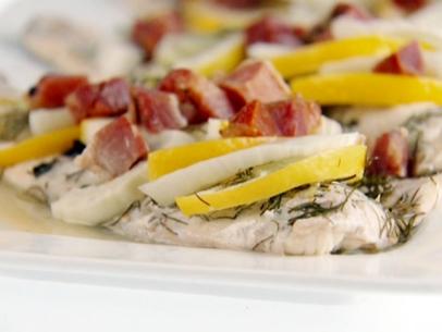 Roasted branzino is topped with pancetta, slices of lemon, and fennel.