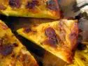 Slices of spanish tortilla made with shredded cheese, chorizo, garlic, onion, and potatoes.