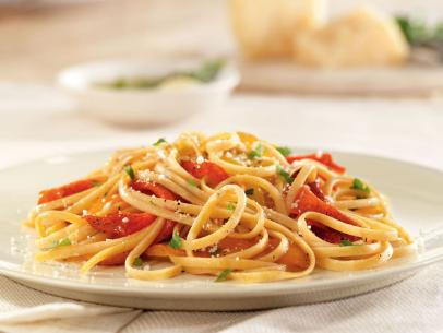 Linguine with roasted peppers, herbs and parmesan cheese on a simple white plate