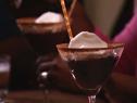 Chocolate pudding topped with whipped cream in martini glasses with cocoa powder on the rims