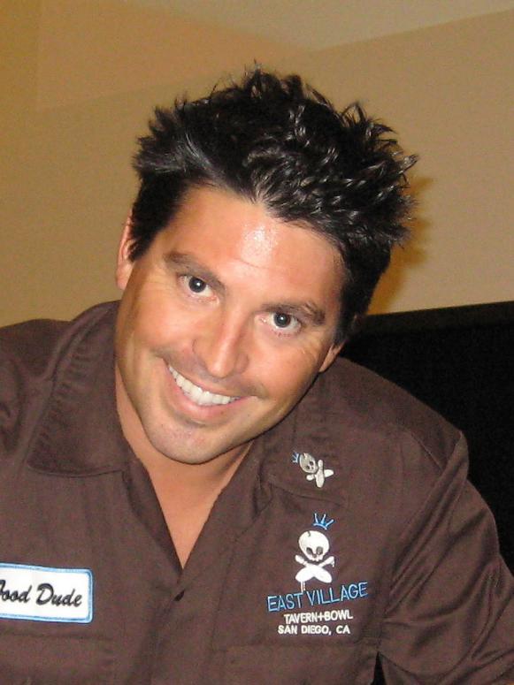 A close-up of former Season 6 Next Food Network Star Kevin Roberts wearing a brown button shirt with a patch that reads Food Dude