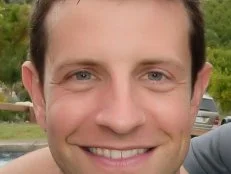 A close-up of former Season 6 Next Food Network Star Paul McCullough smiling while wearing a gray shirt