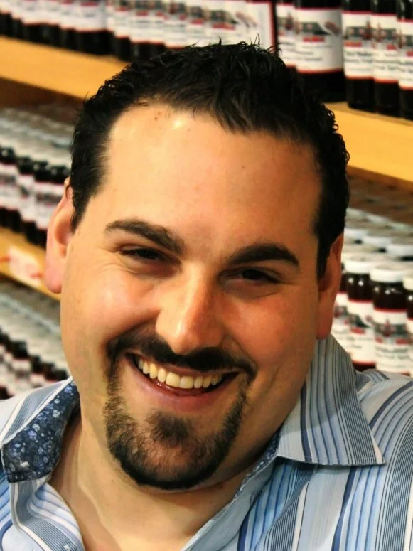 A close-up of former Season 6 Next Food Network Star Thomas Grella smiling while wearing a blue and white striped shirt